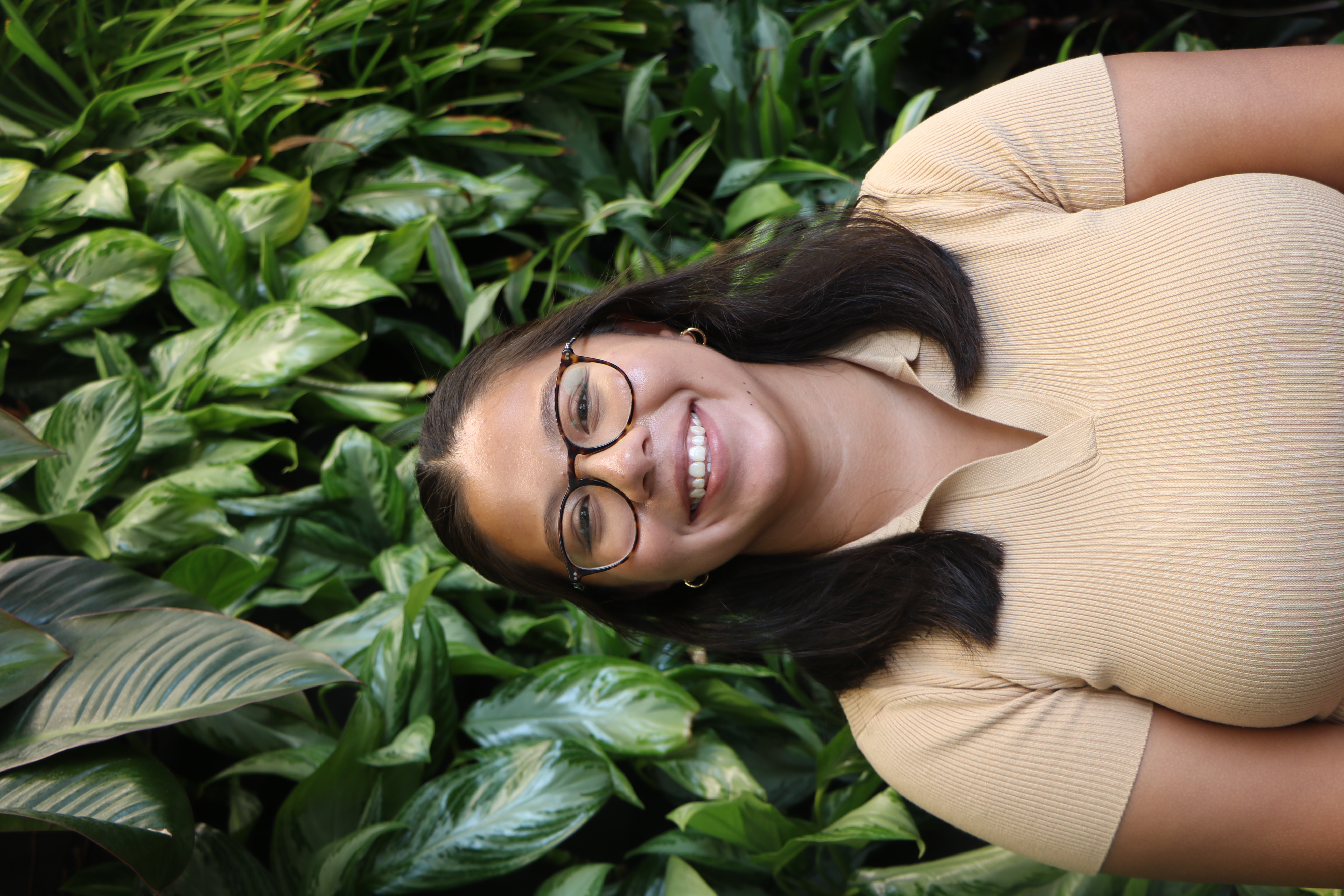 Photo of Veronica Lijeron wearing a yellow shirt in front of a greenery wall.