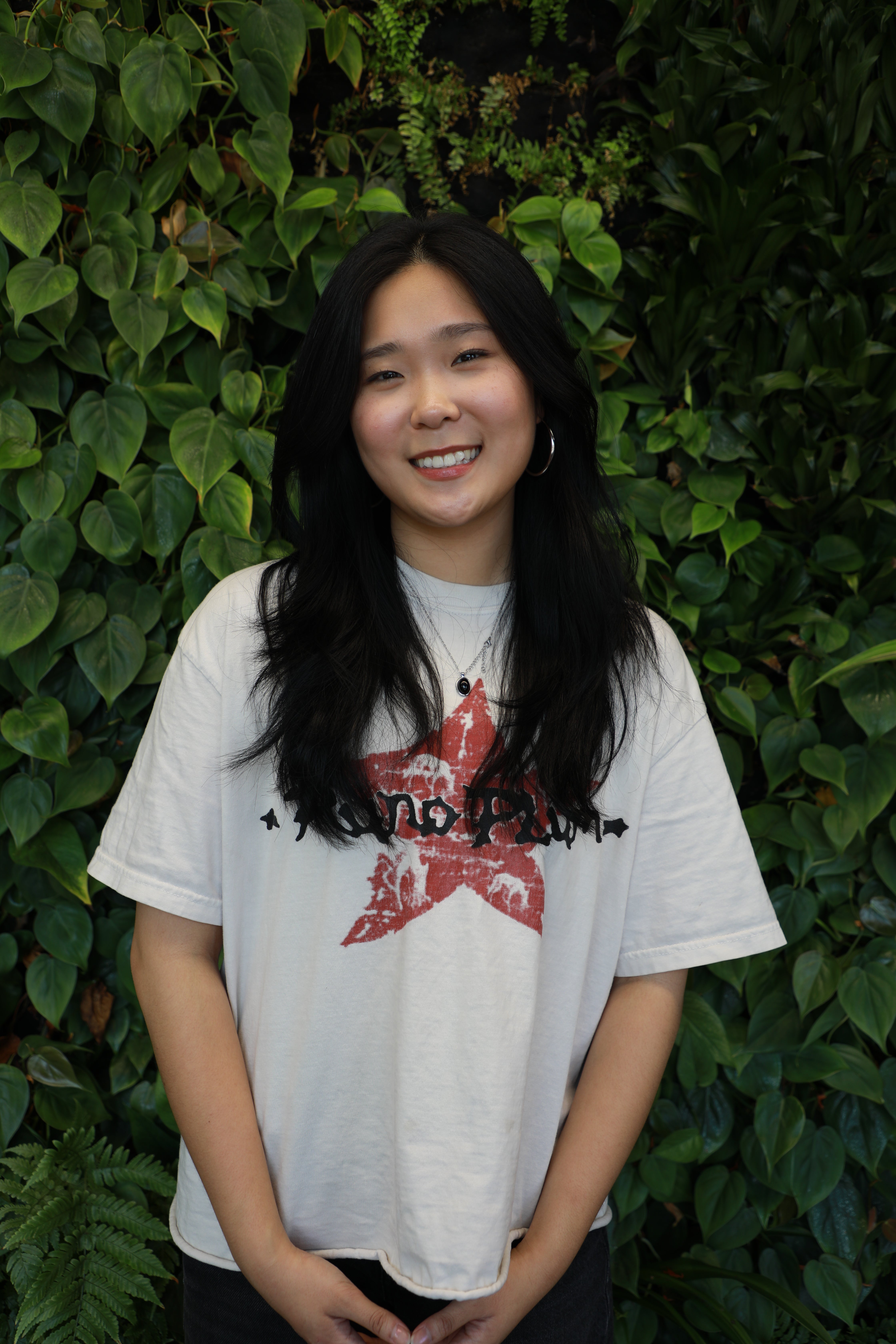 Jiun smiling in front of green wall.
