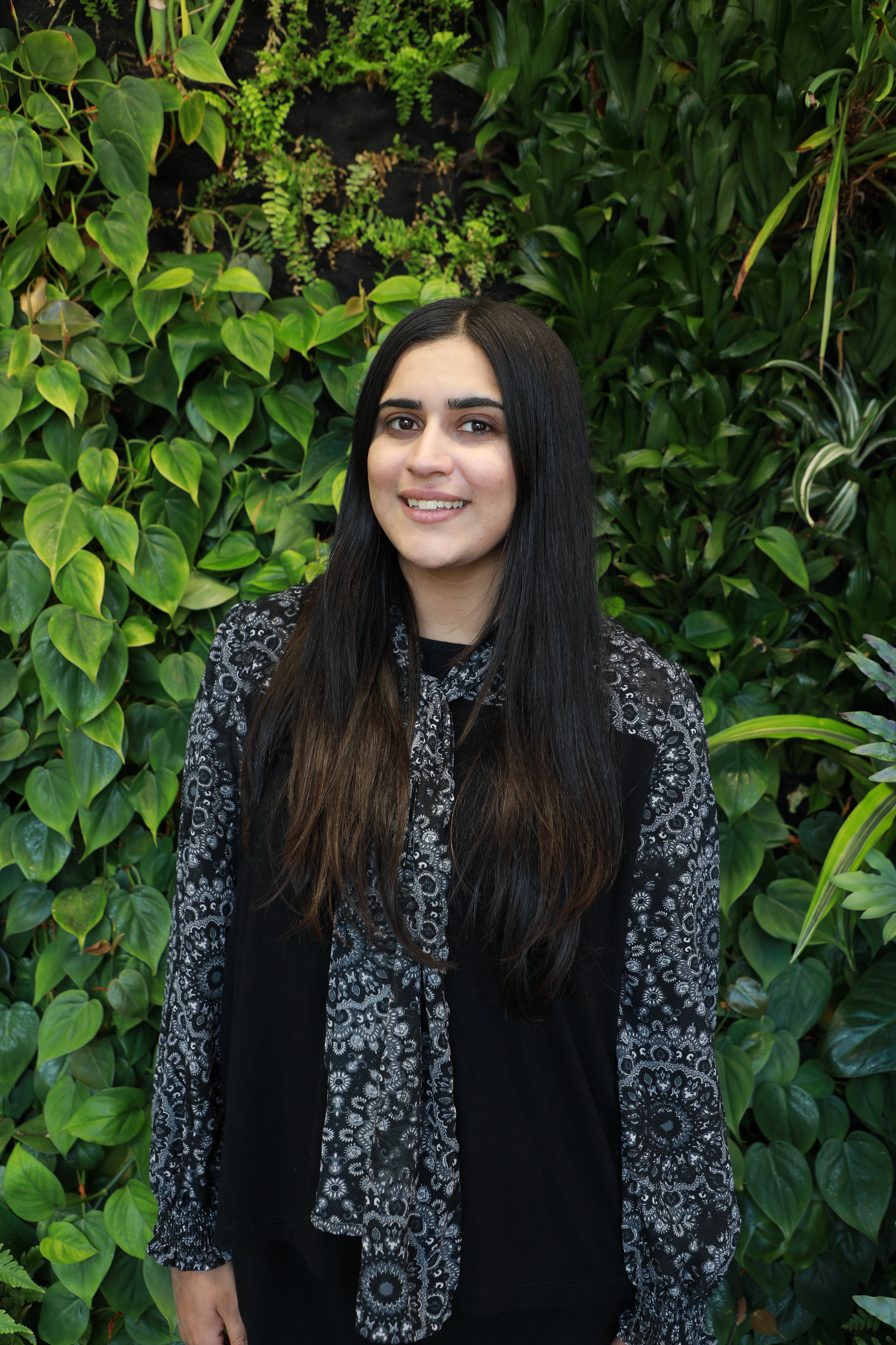 Fatima smiling in front of green wall.