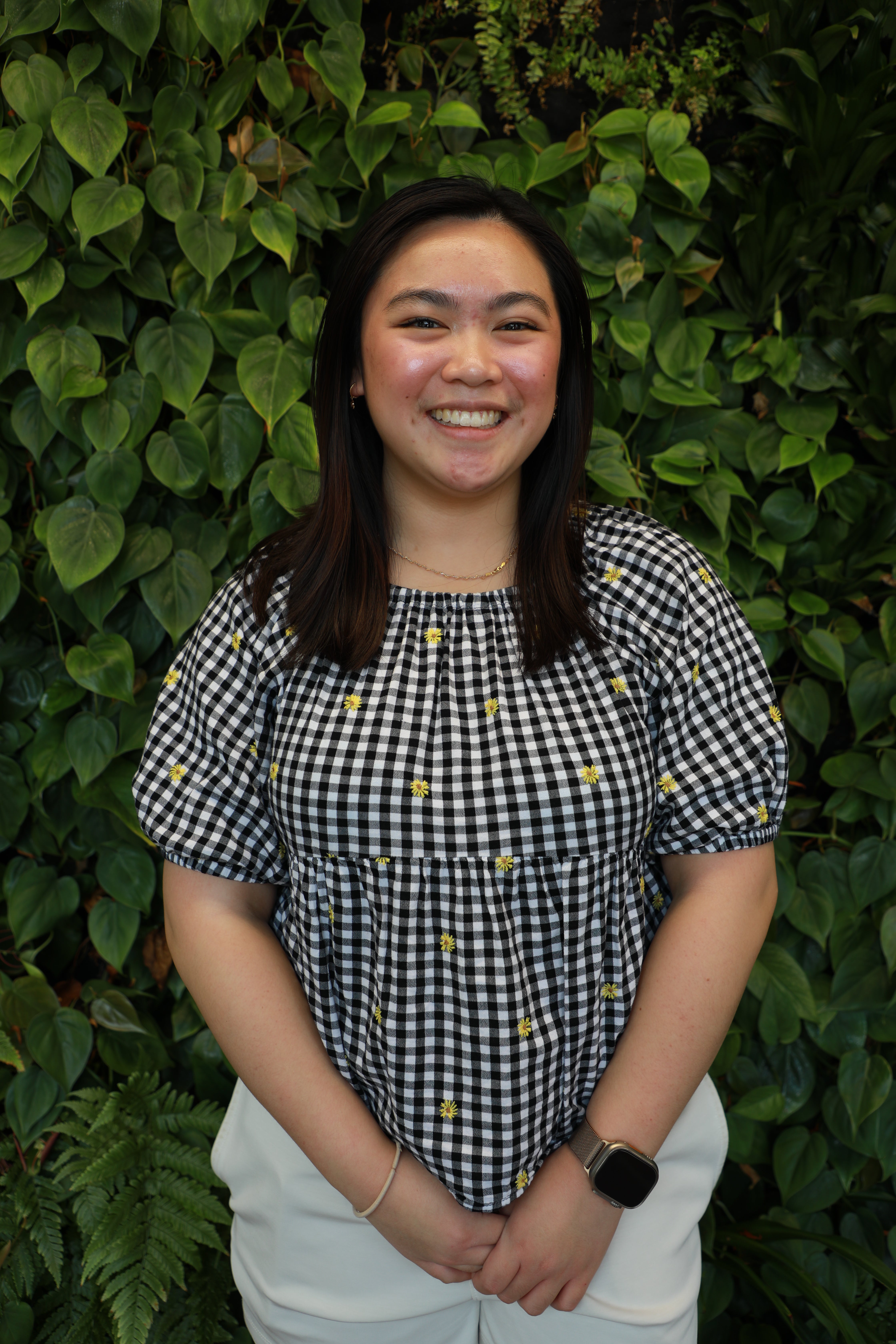 Machiko Koga smiling in front of green wall.