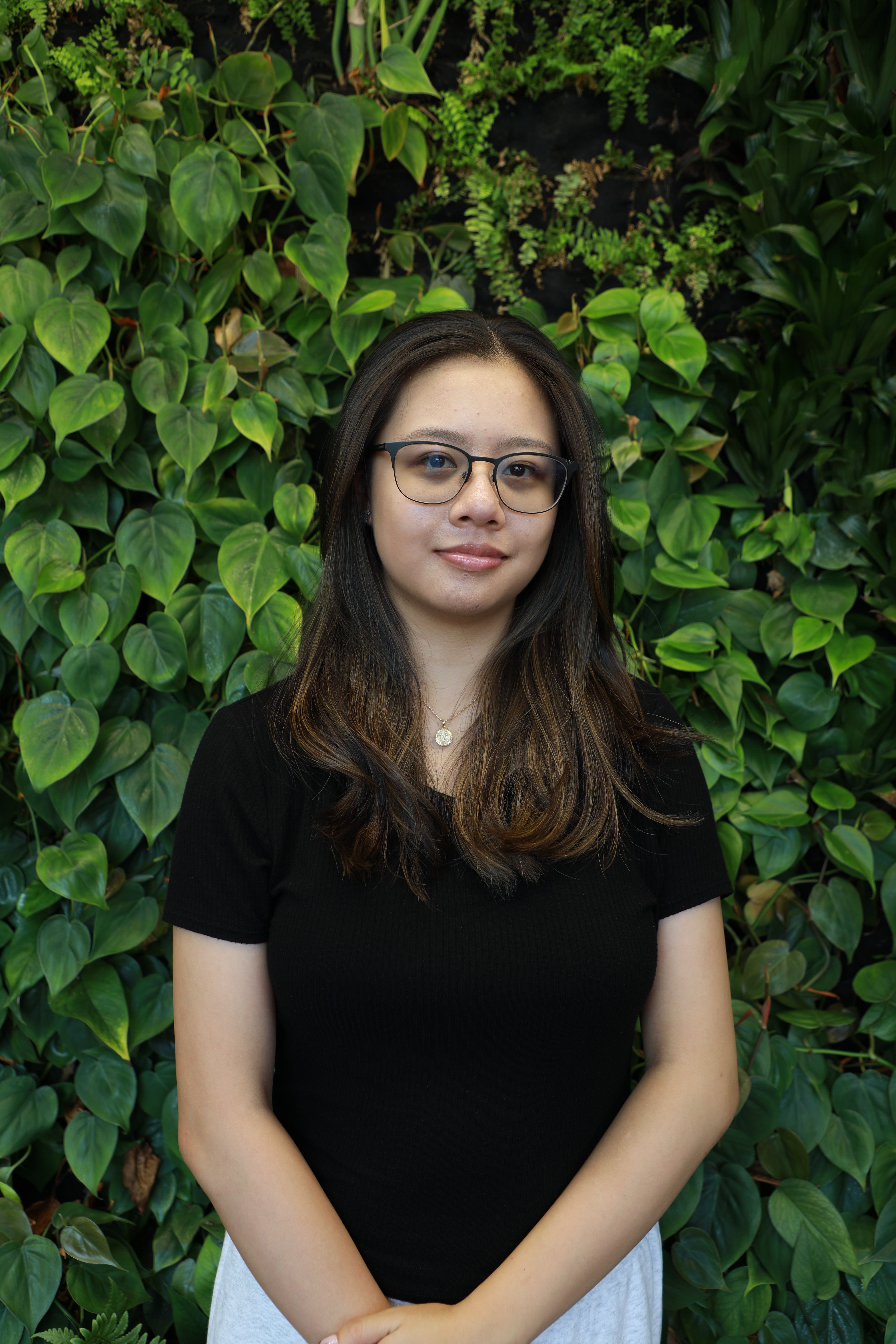 Nicole smiling in front of green wall.