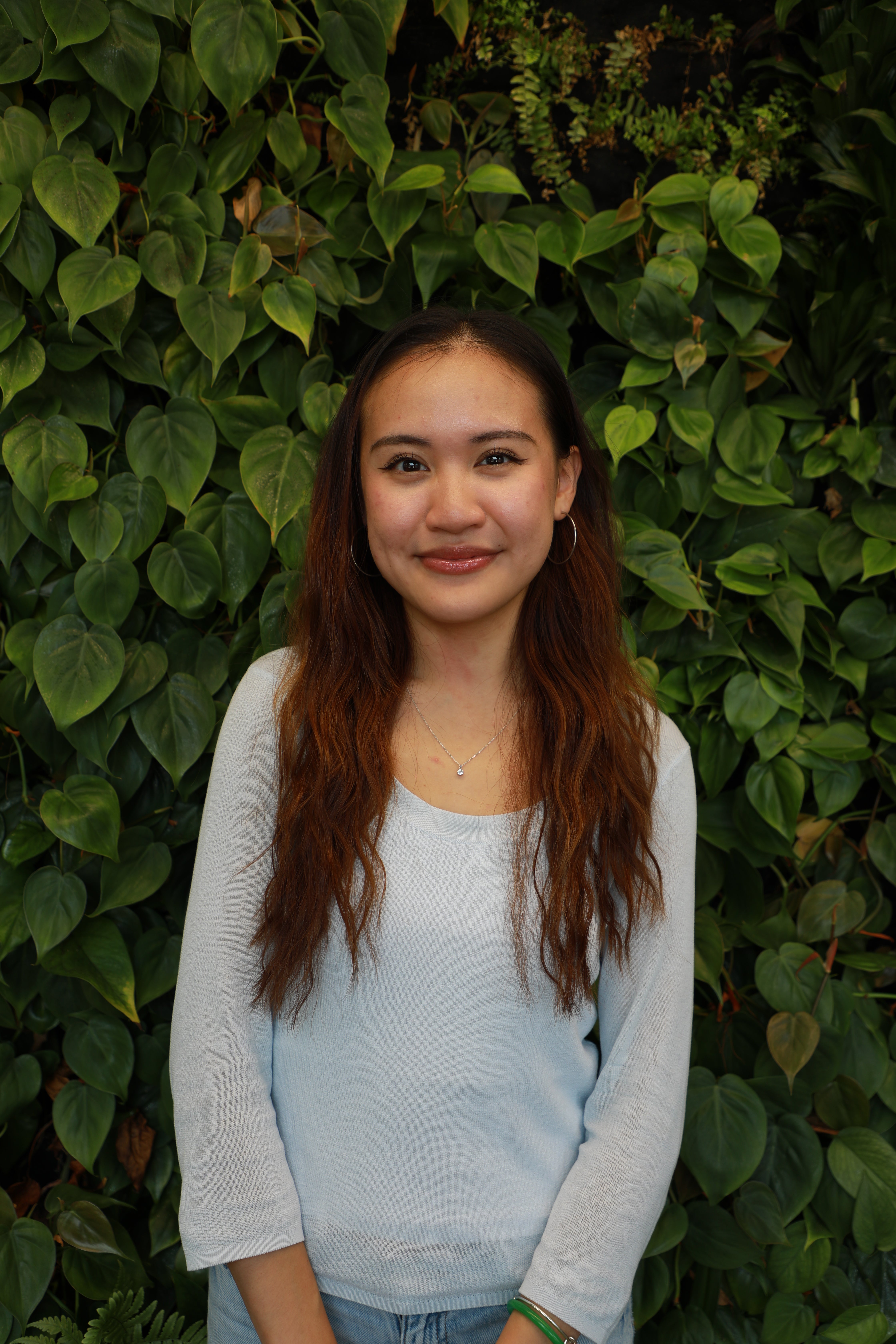 Mimi smiling in front of green wall.