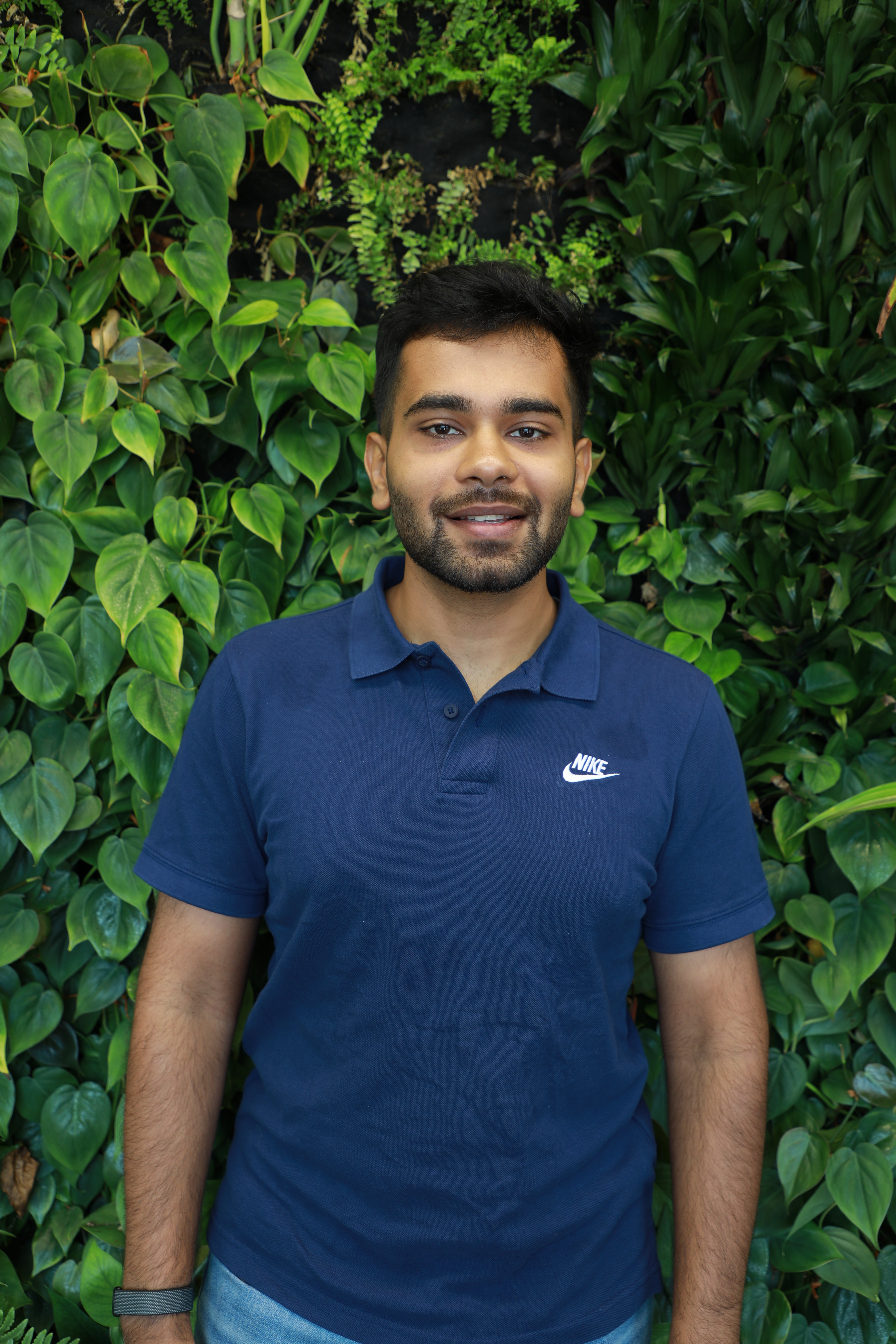 Rushil smiling in front of green wall.