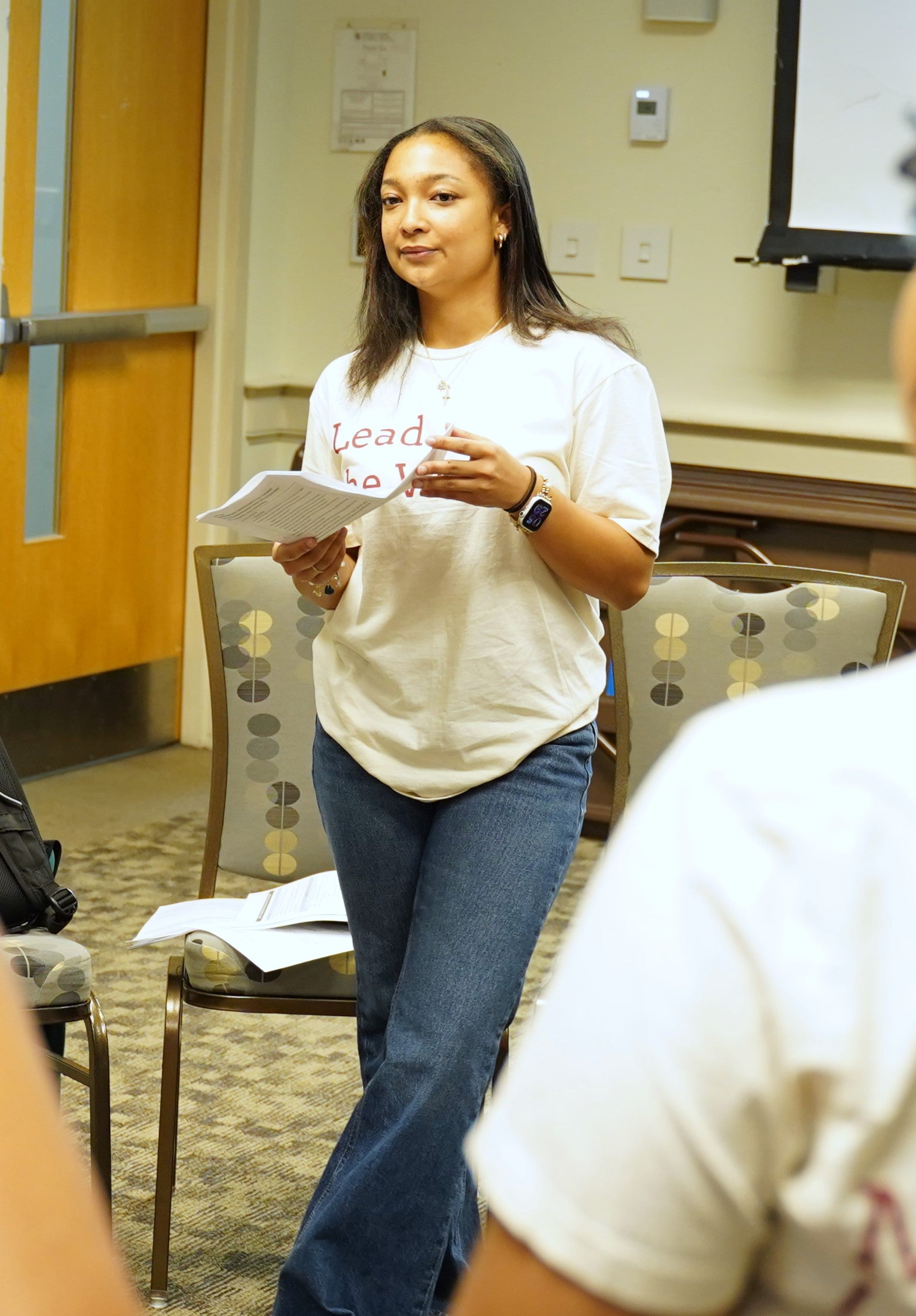 Photo of a previous facilitator standing with curriculum in hand, facilitating and activity