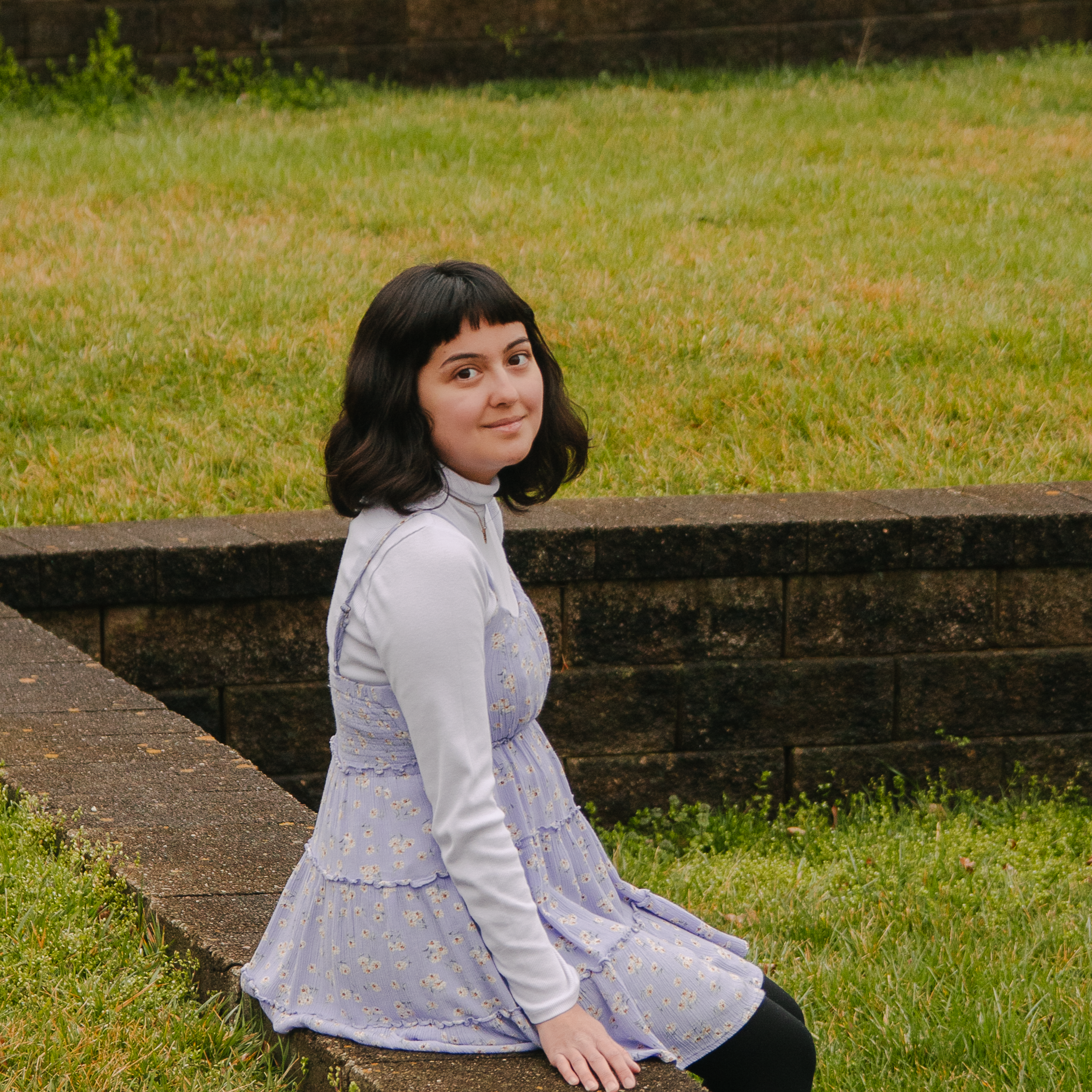 woman sitting outside with head turned to face the camera
