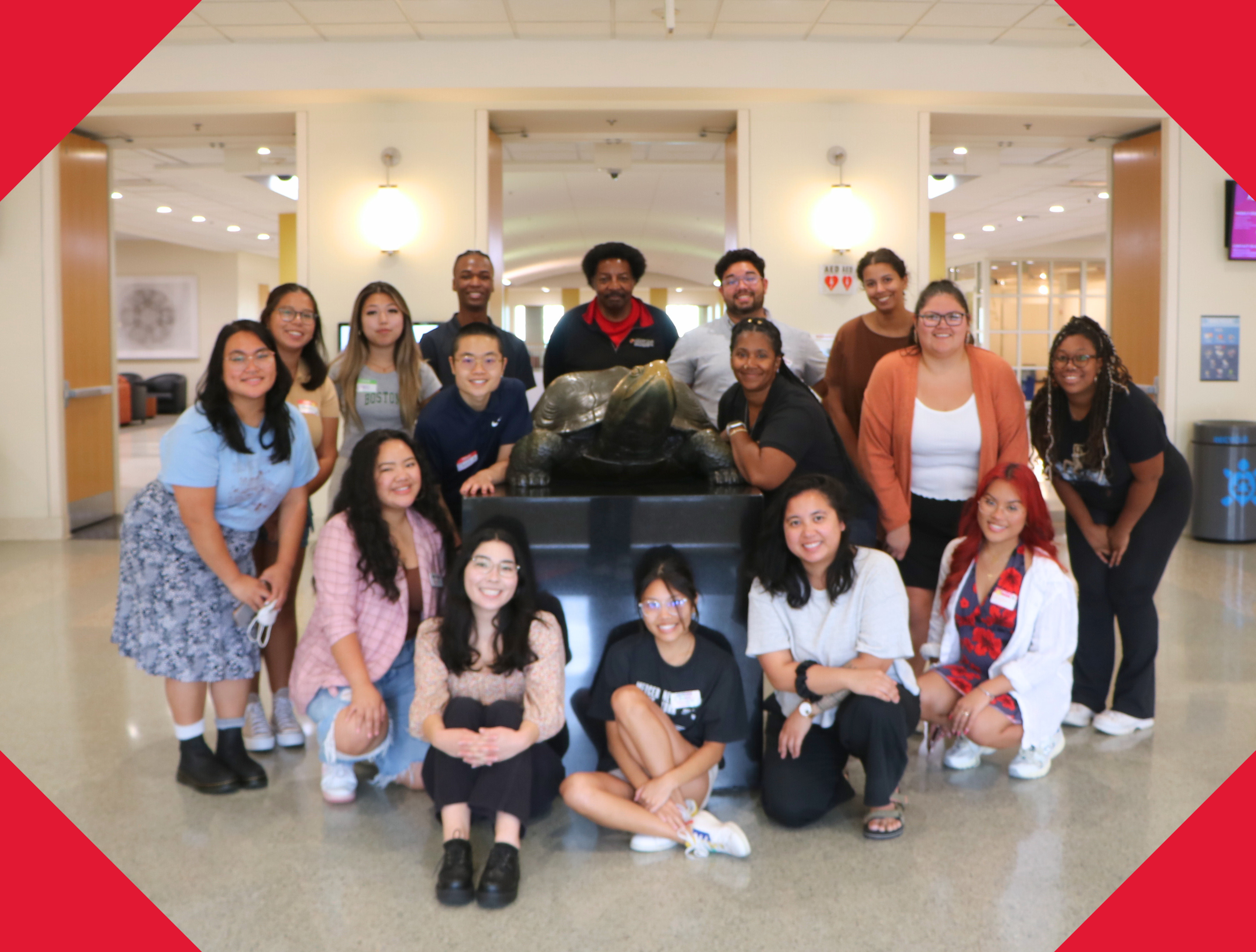 Group photo of all 15 members of the MICA staff, smiling around the Stamp Testudo statue.