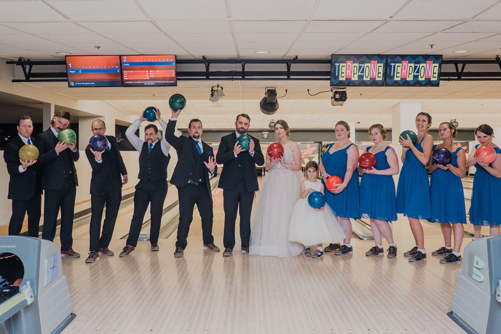 wedding party posing while holding a bowling ball