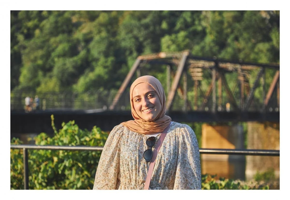 Photo of Rasha Alkhateeb, young woman in hijab standing against an outdoor scene