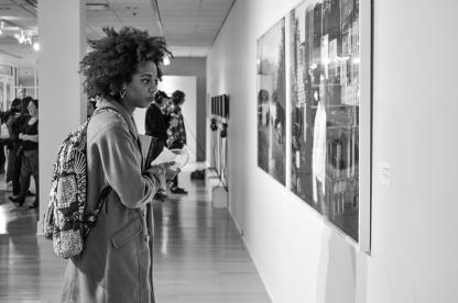 People view contemporary artwork hanging on walls inside the Stamp Gallery.