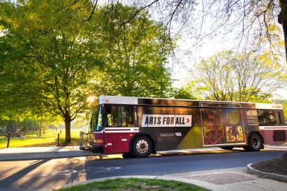 A ShuttleUM bus with an “Arts for All” bus wrap drives past McKelding Mall.