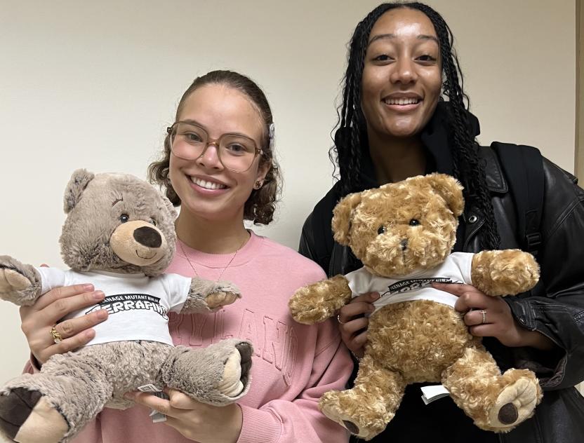 Two smiling women hold stuffed bears