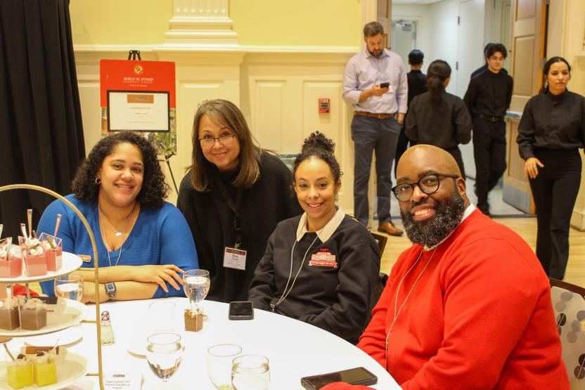 Four Stamp staff members smiling around a dining table during lunch at a conference.