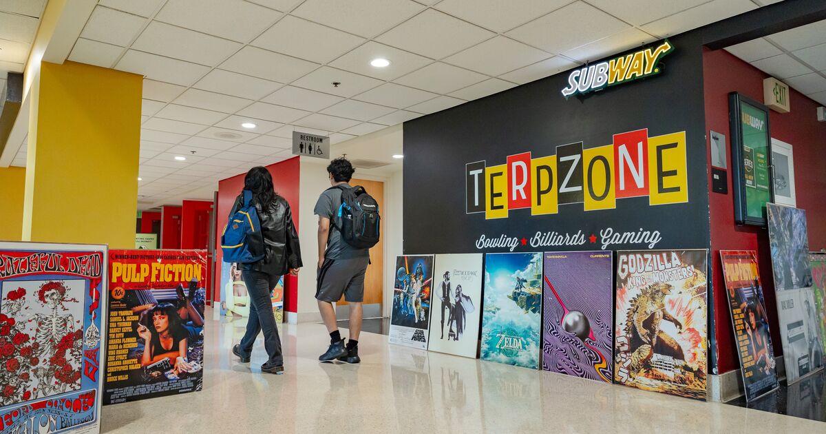 Two UMD students walk past a display of posters outside of the TerpZone in STAMP.