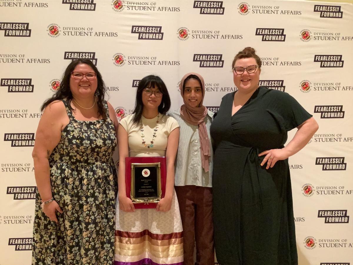 A photobooth photo of an award recipient and 3 banquet guests