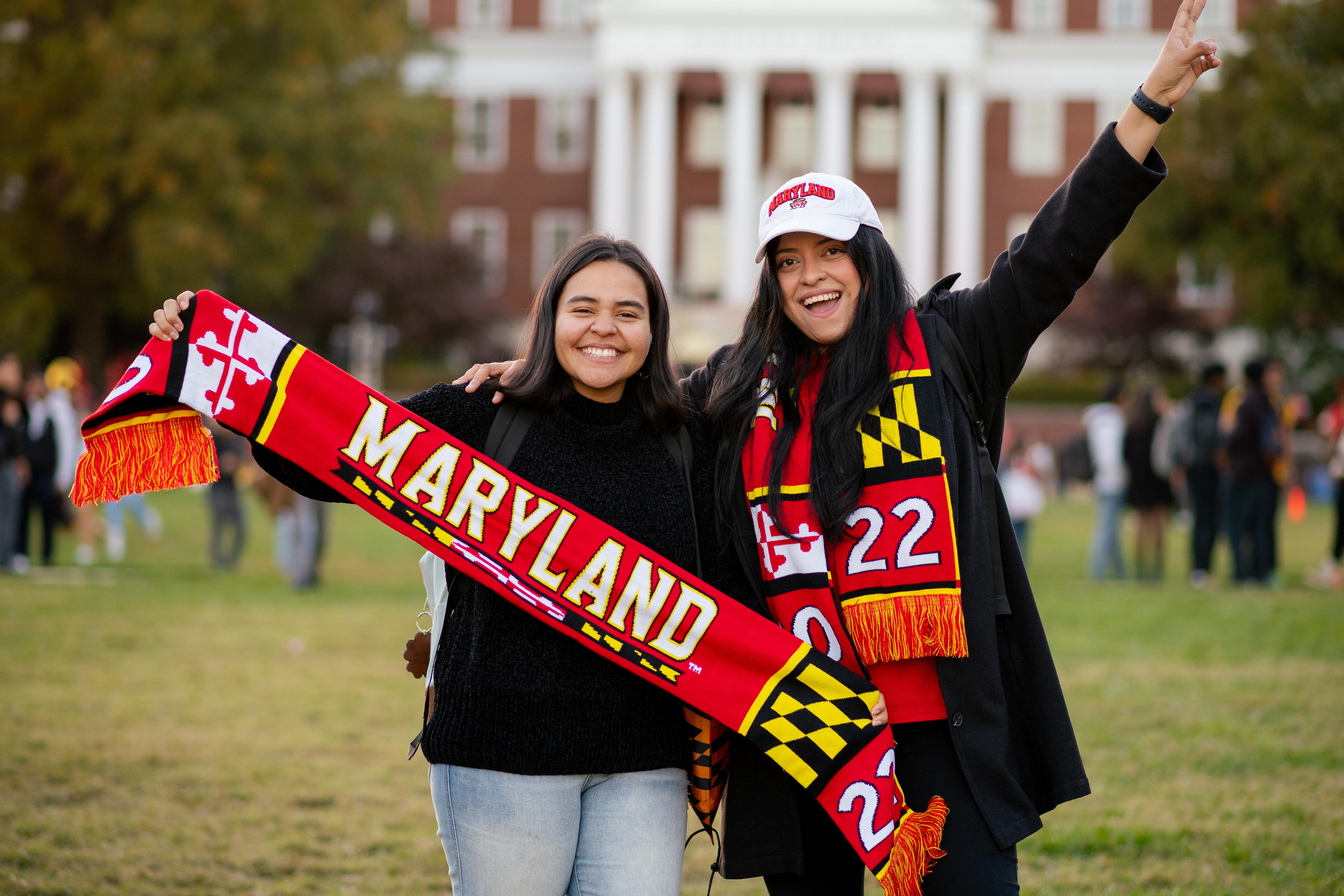 students holding out a Maryland scarf