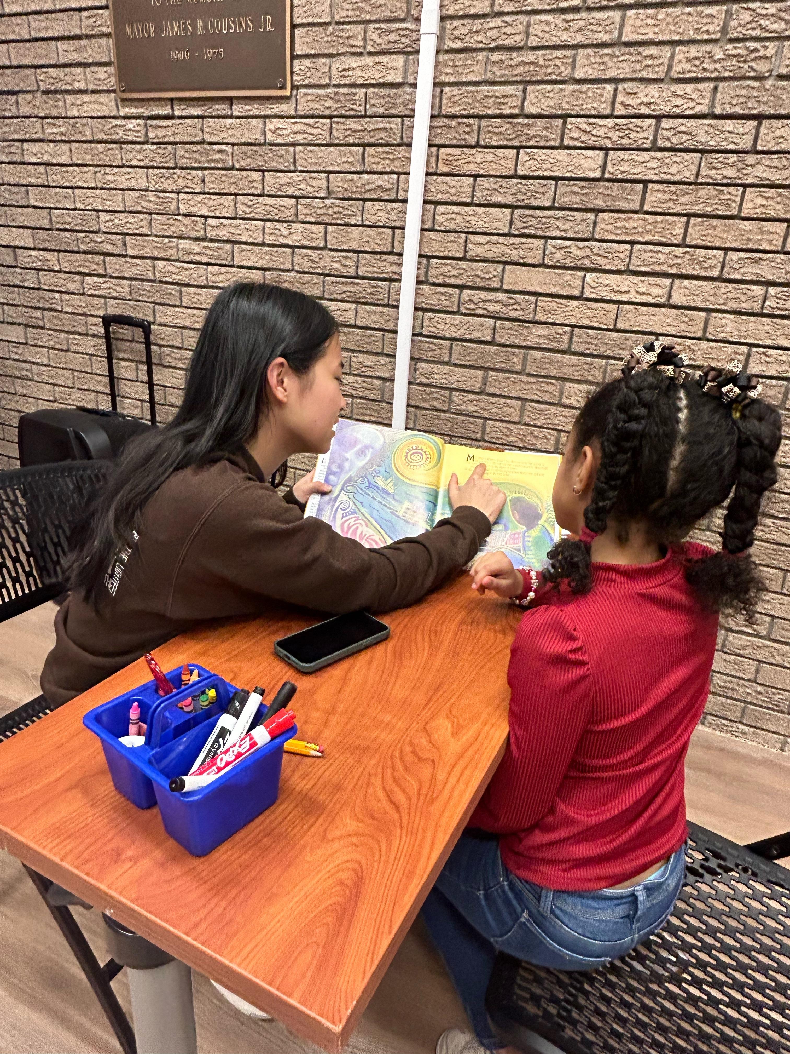 UMD student reading a book with younger child