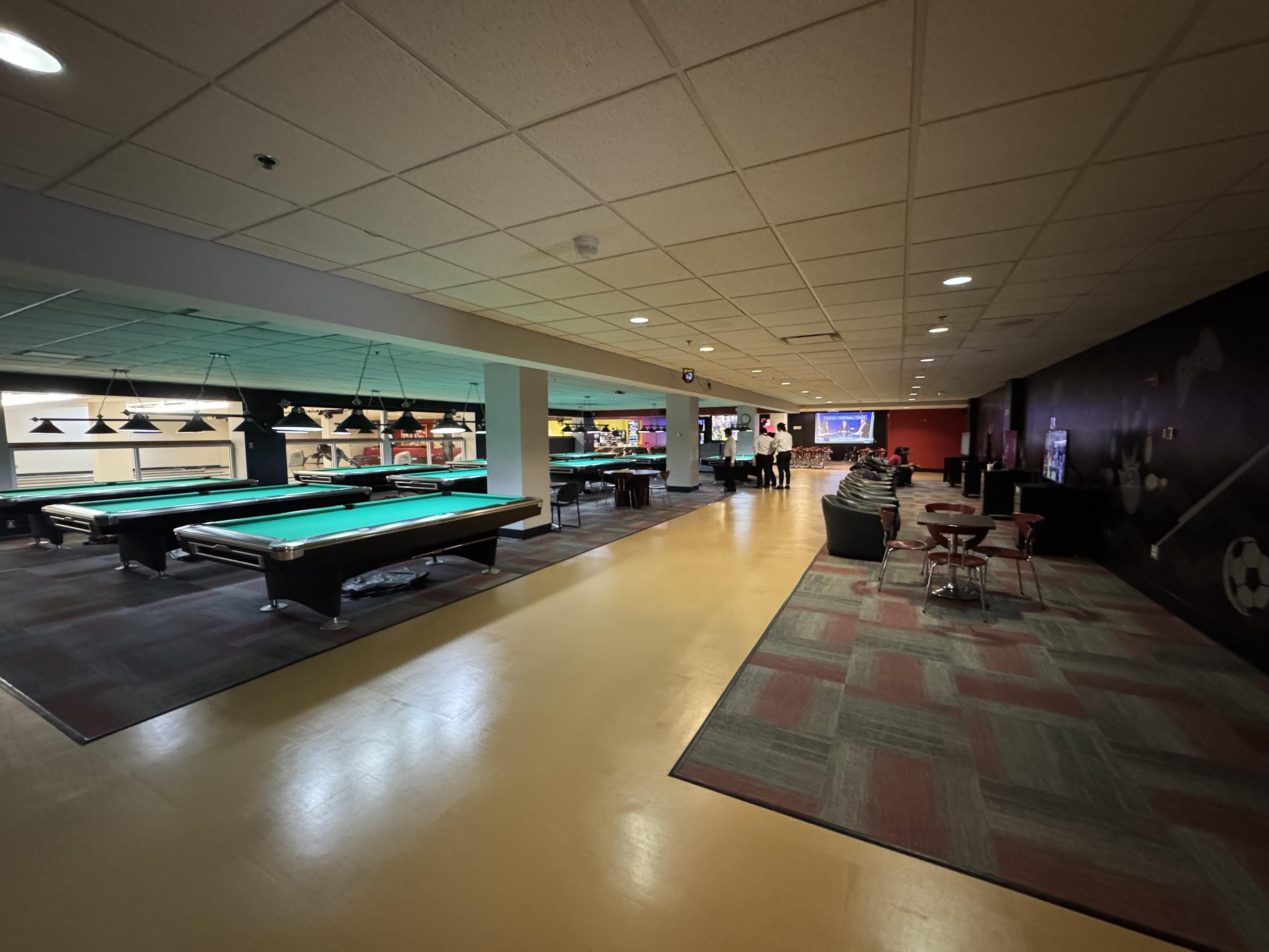 View of Billiard Table and Video Gaming Stations. Large projector screens in the distance.