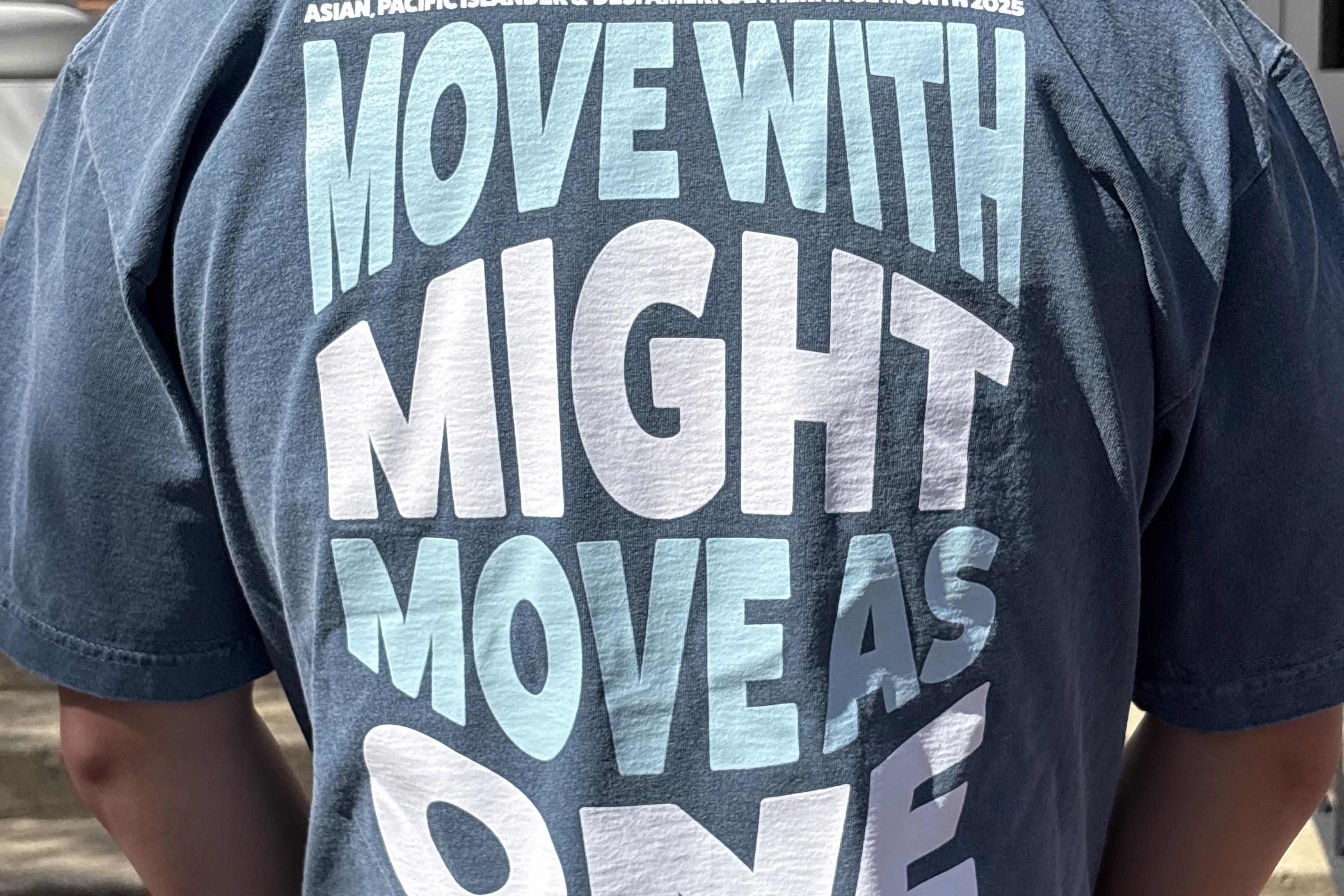 back of a shirt that says "Move with might move as one"
