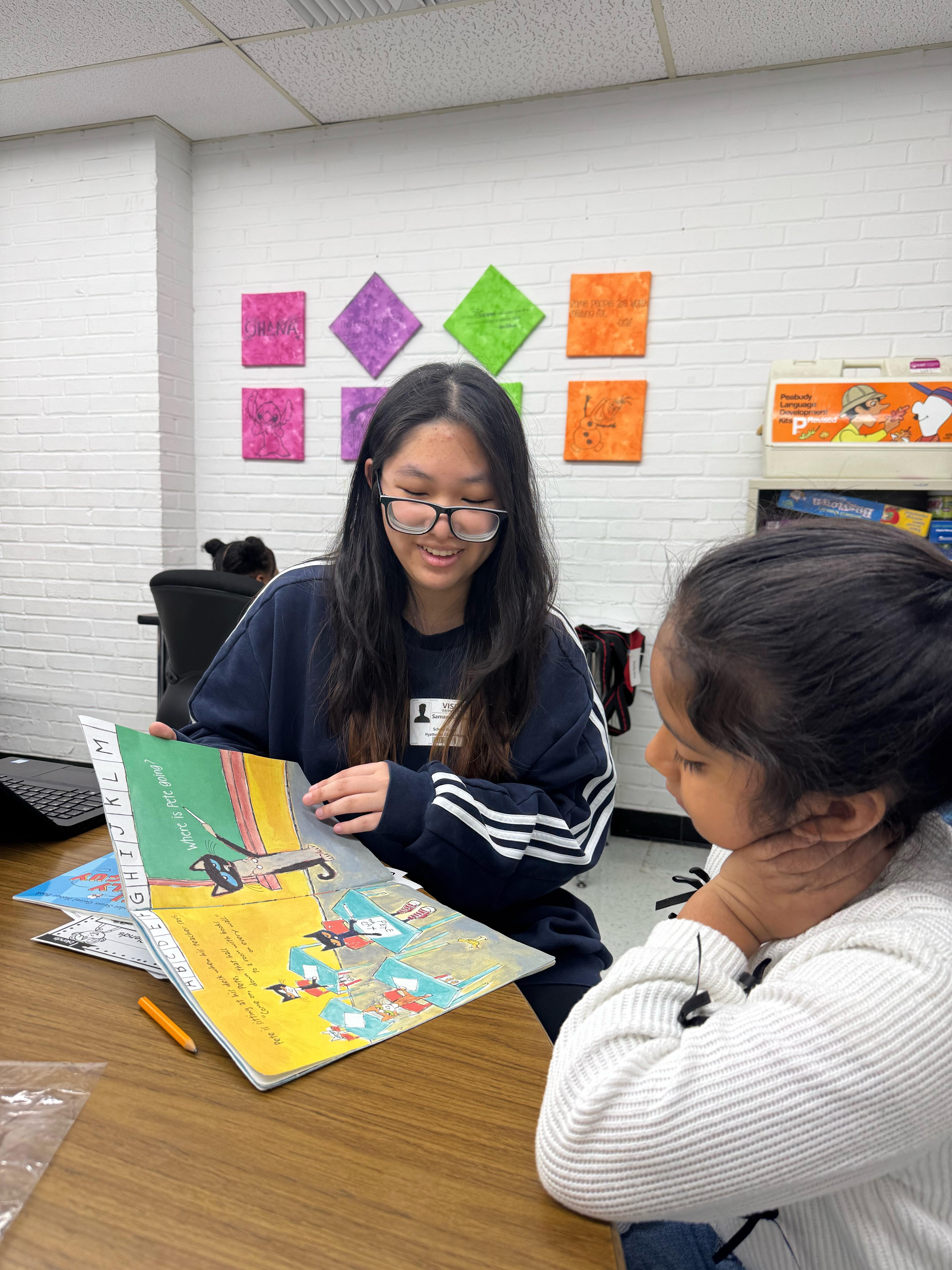 UMD student mentoring elementary student, reading a book