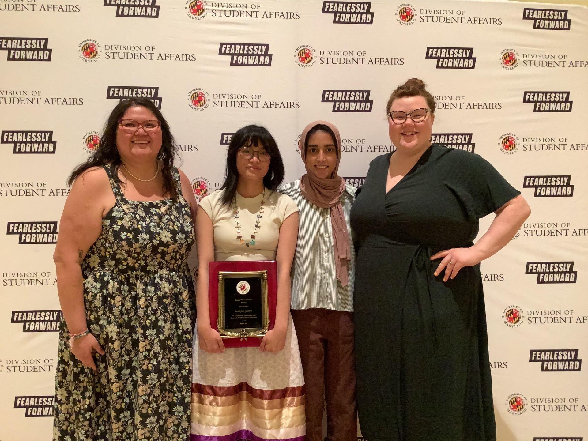 A photobooth photo of an award recipient and 3 banquet guests