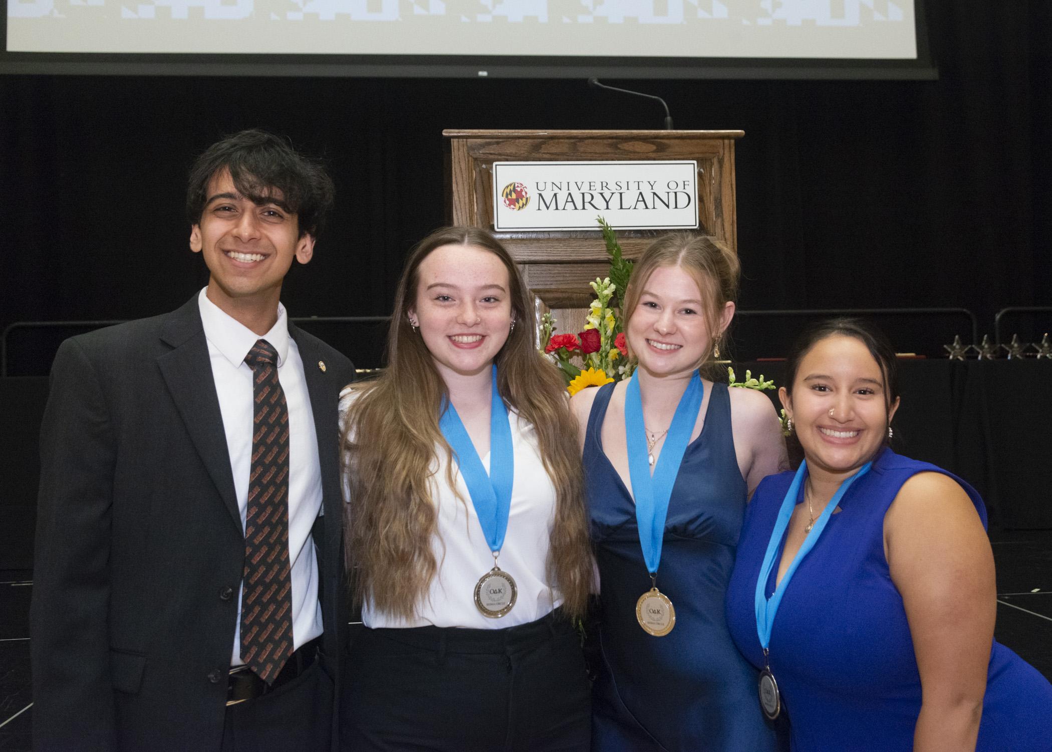 A photo of four award recipients. 3 of them are wearing their ODK Top Ten Freshamn Medallions around their necks