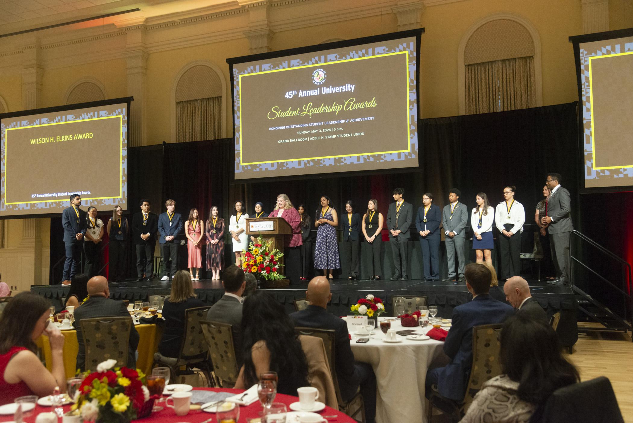 A photo of the 2026 Maryland Medallion Society on stage while Dr. Patty Perillo is spaking at the podium