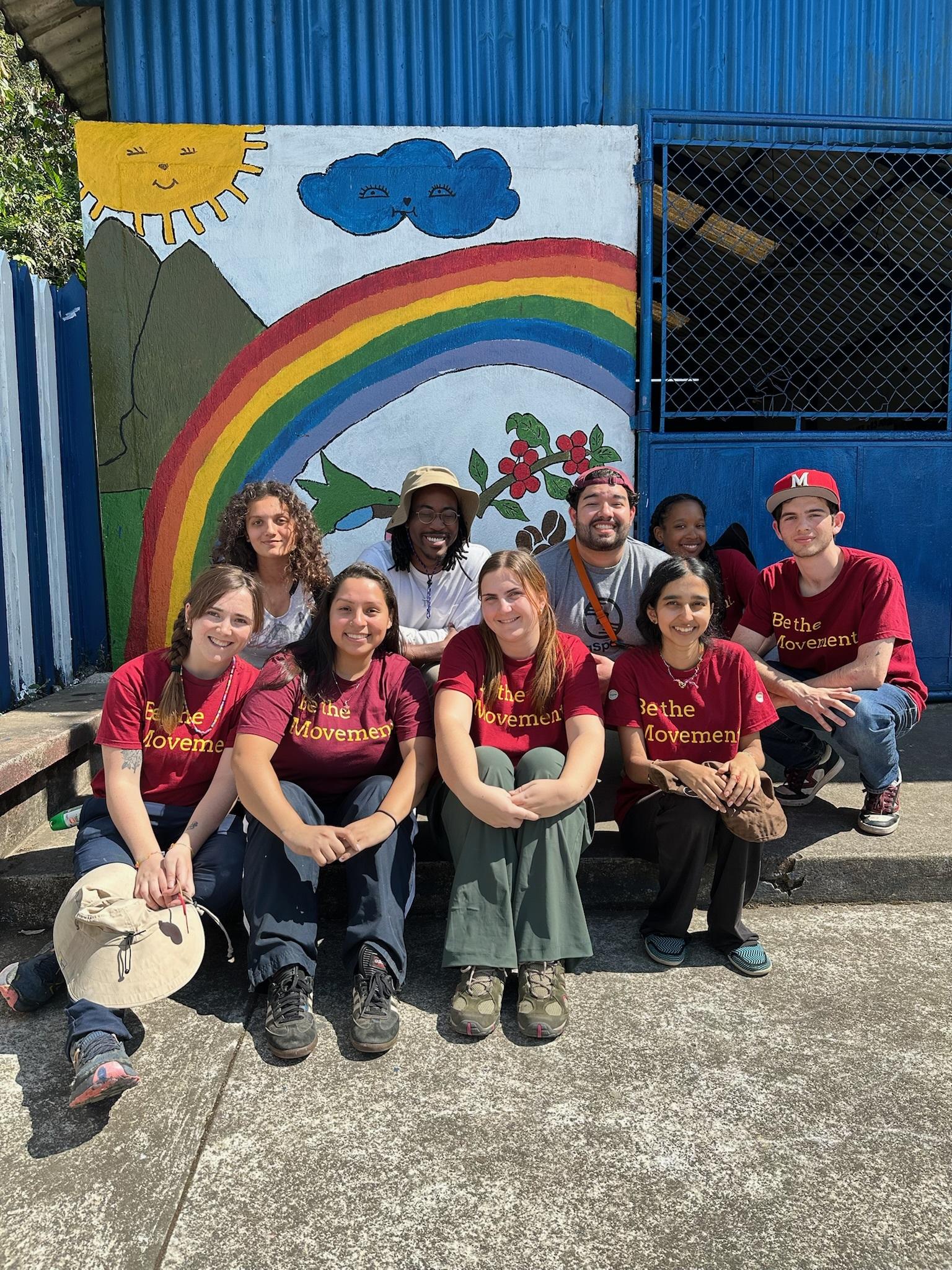 An AB team poses in front of a mural they painted on a school in the community of Los Andes, Guatemala. 
