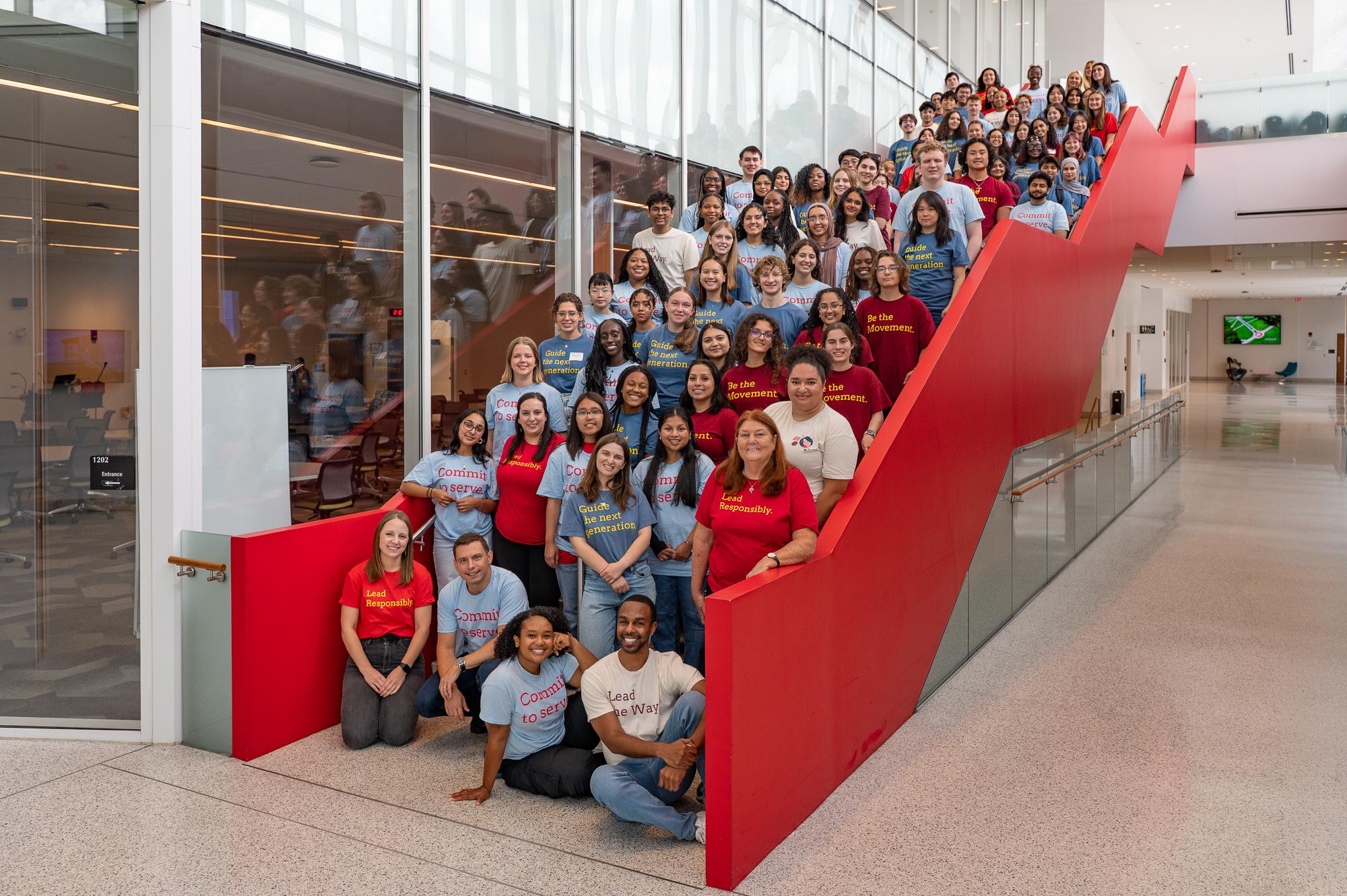 group of students wearing different colored shirts standing on tall stairwell
