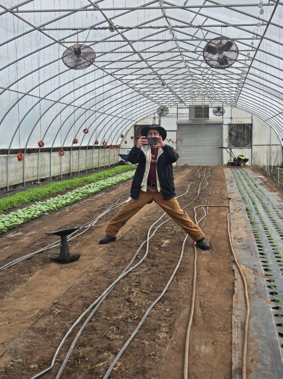 Staff Advisor taking a photo of their team in a greenhouse where they were doing service.