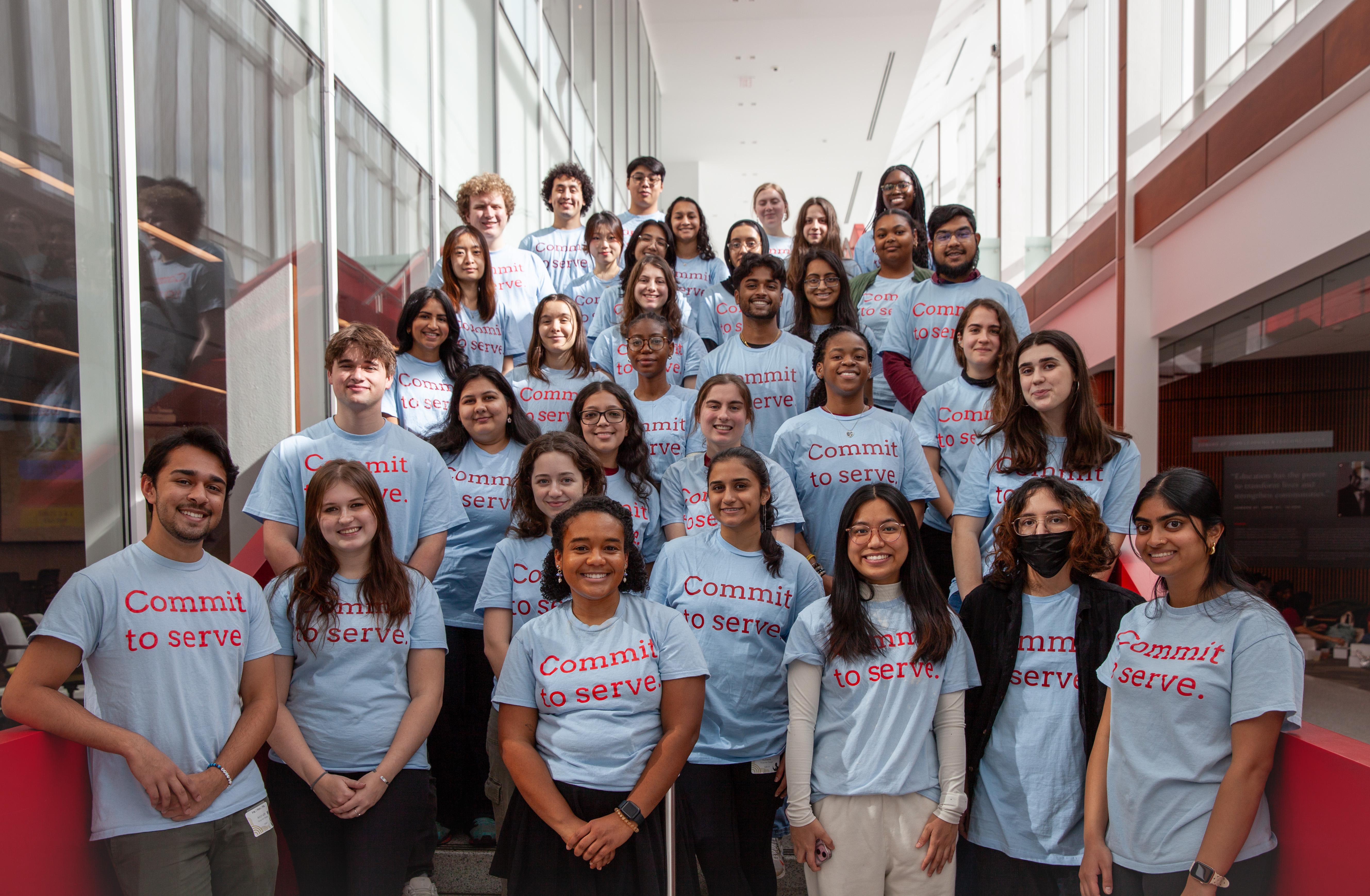 30+ students wearing matching shirts, standing on staircase