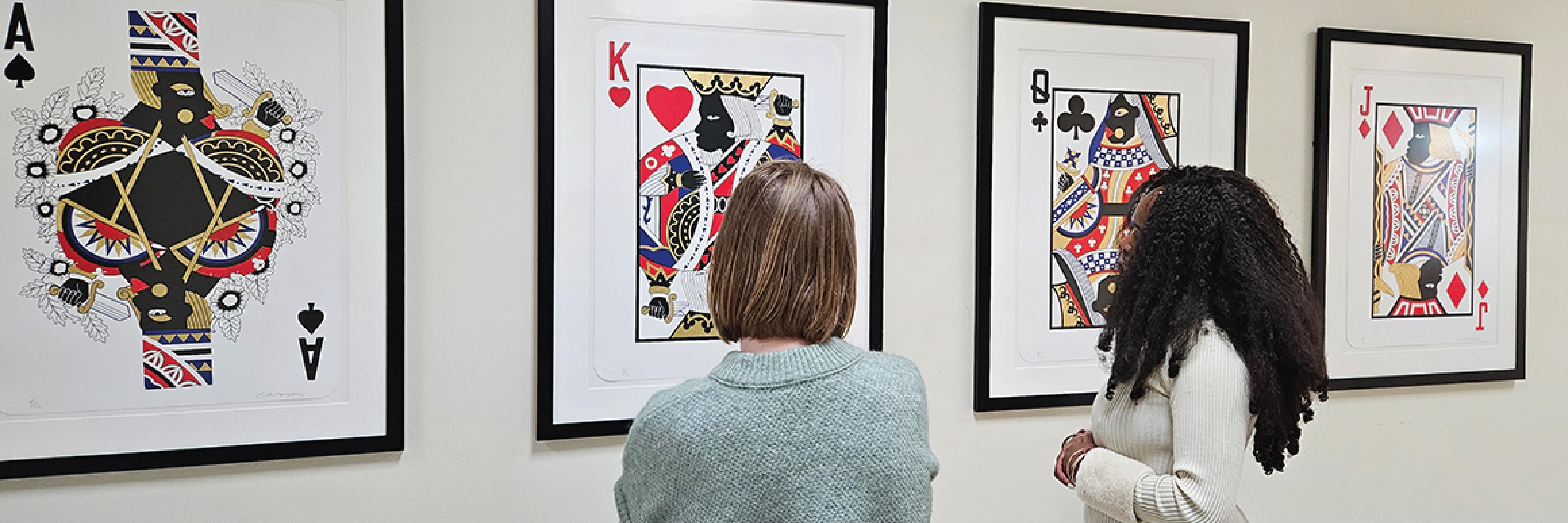 Two women look at a series of prints displayed on the wall of The Adele H. Stamp Student Union—Center for Campus Life 