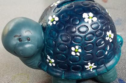 ceramic turtle painted shades of blue with white flowers.