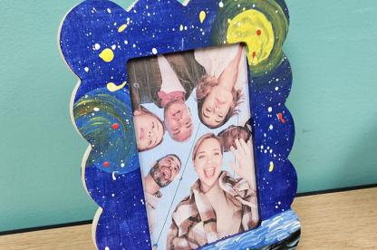 Painted wooded picture frame with bubbled edges and a photo of friends inside.