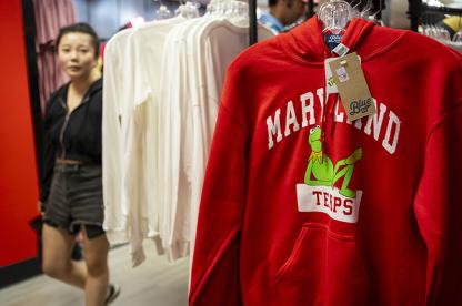 A visitor passing by a red Maryland sweatshirt with Kermit at the UMD Bookstore.